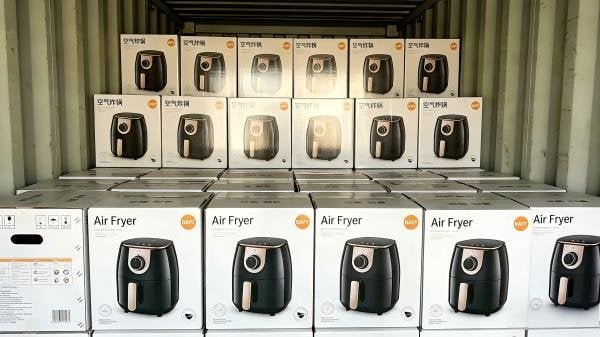 A shipping container being loaded with tightly packed boxes of air fryers.