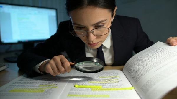 A person reviewing a detailed contract with a magnifying glass, focusing on key clauses.